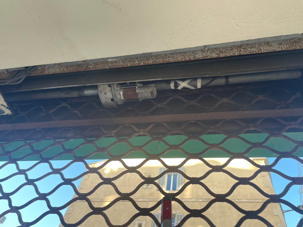 Grille métallique articulée motorisée vue de l’intérieur, axe et moteur au-dessus du tablier