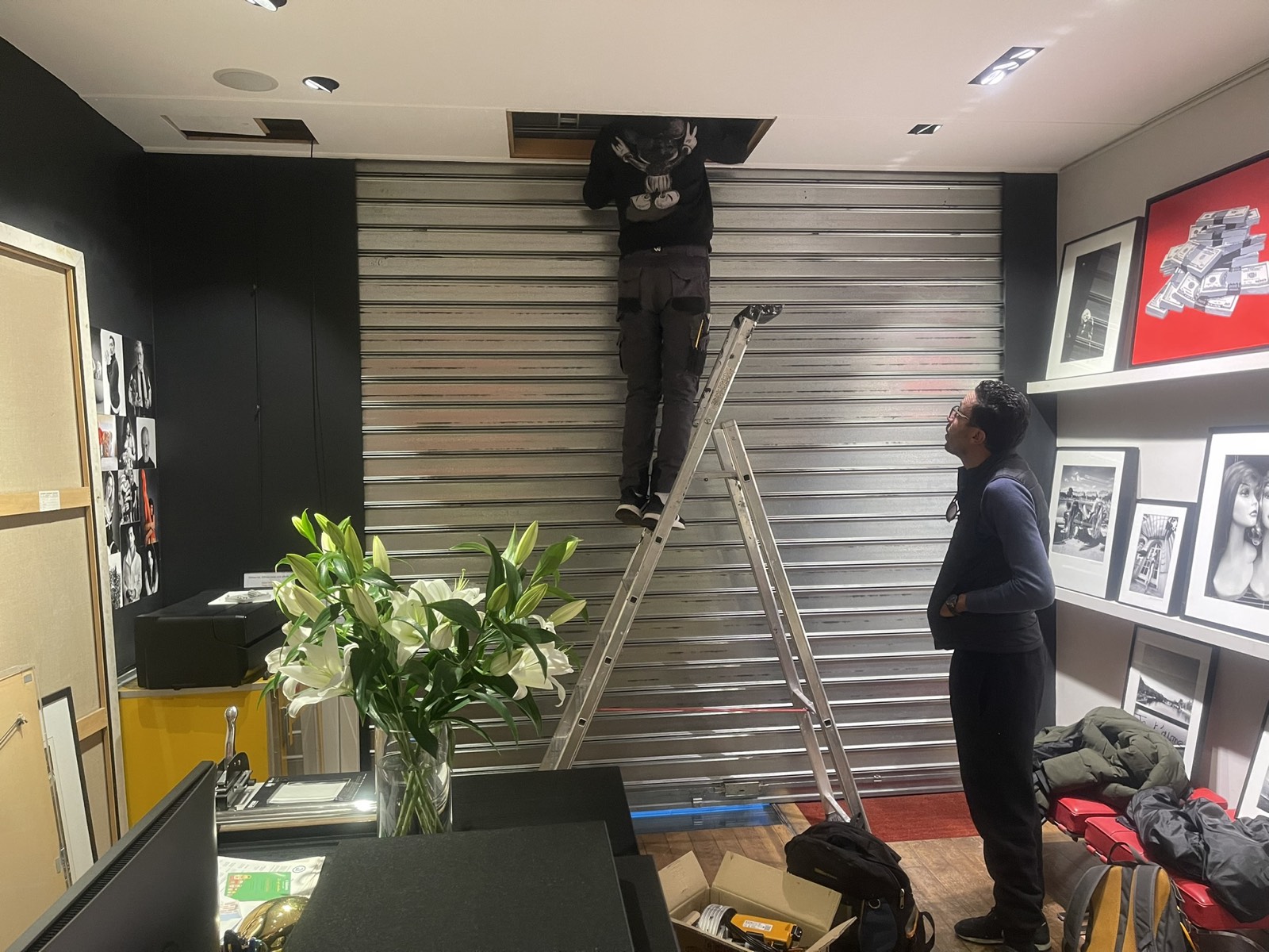Technicien sur une échelle intervenant sur le coffre du rideau métallique d’une galerie d’art