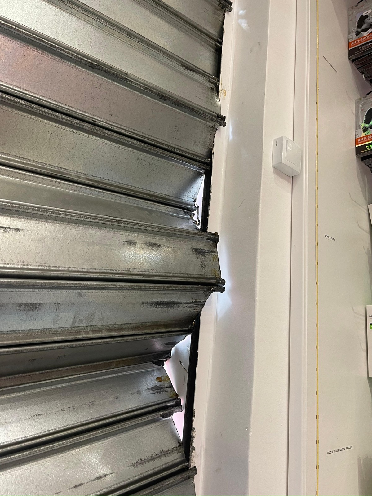 Tablier de rideau métallique sorti de sa coulisse, lames déformées